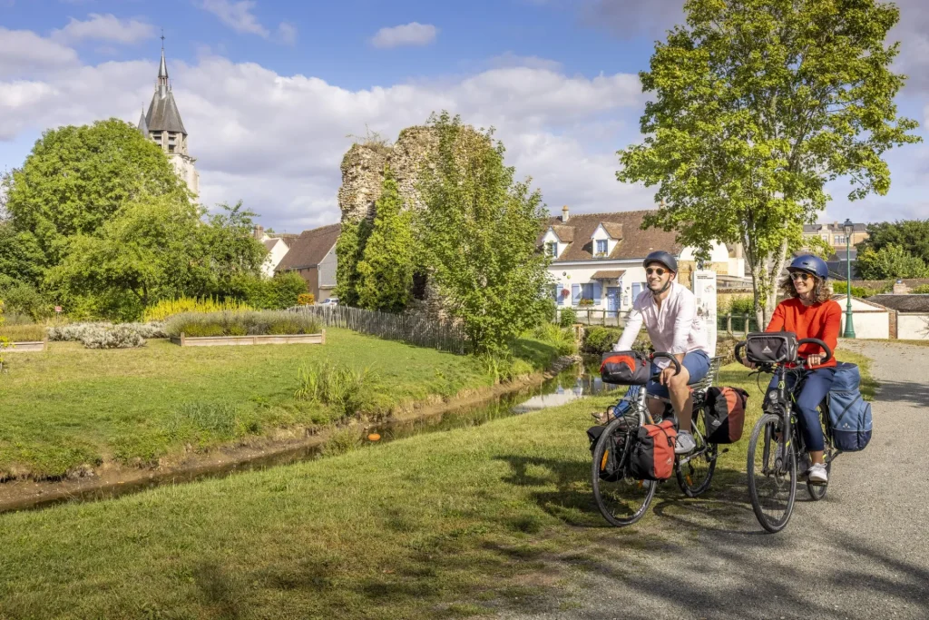 Deux cyclotouristes pédalent le long d'un petit cours d'eau à Illiers-Combray