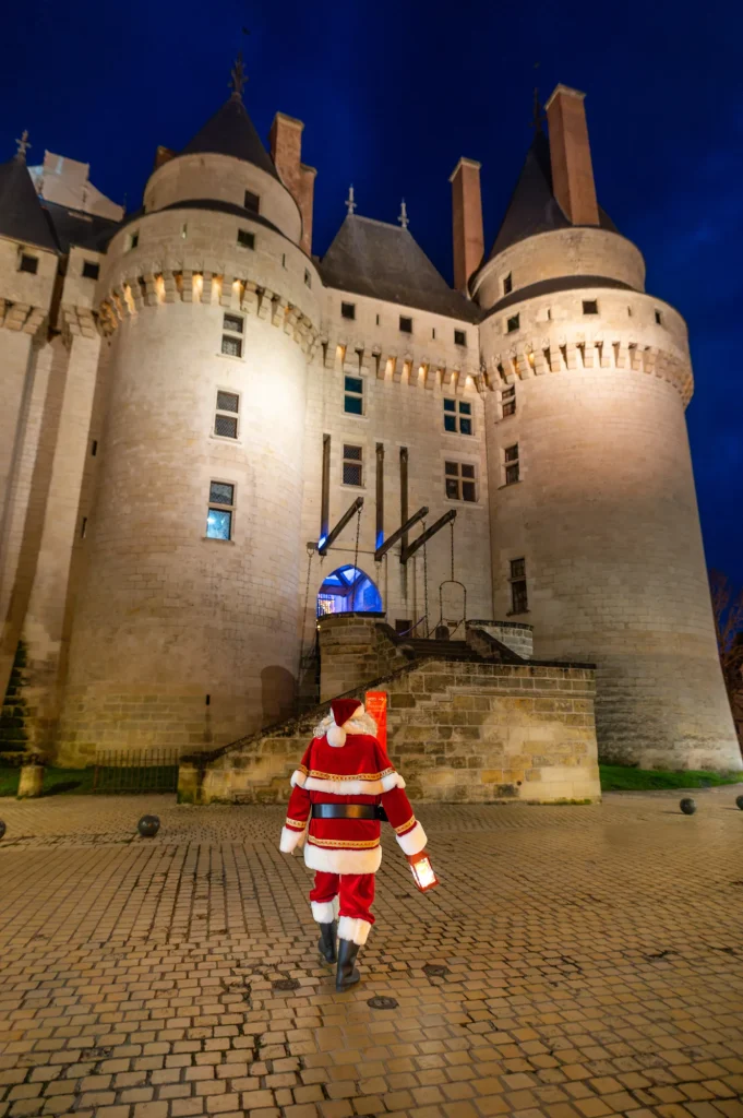 Père Noël devant le pont-levis du château de Langeais illuminé