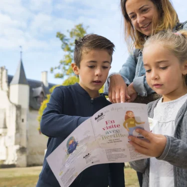 Jeunes enfants et leur mère à Chinon lisant des instructions sur un dépliant