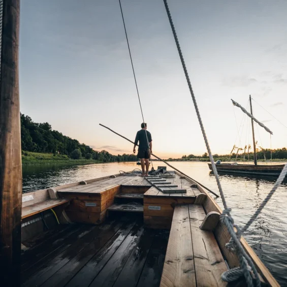 Homme debout sur un bateau sur la Loire qui regarde le coucher de soleil