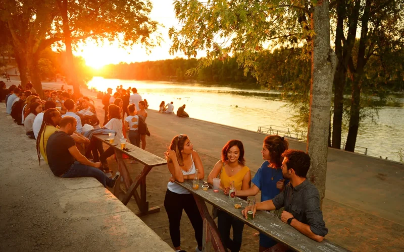 Sur les bords de Loire, en soirée, des groupes de jeunes gens attablés et qui se désaltèrent