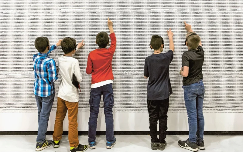 5 enfants avec un casque audio devant un mur en train de rechercher de toutes petites images